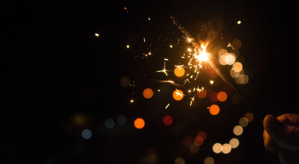 Hand holding a sparkler against a black background