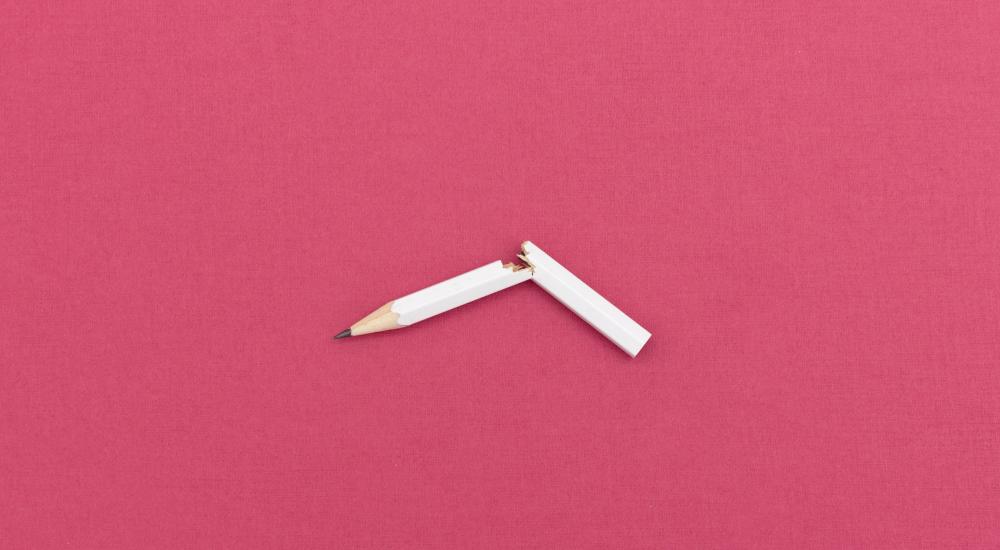 broken white pencil on pink background