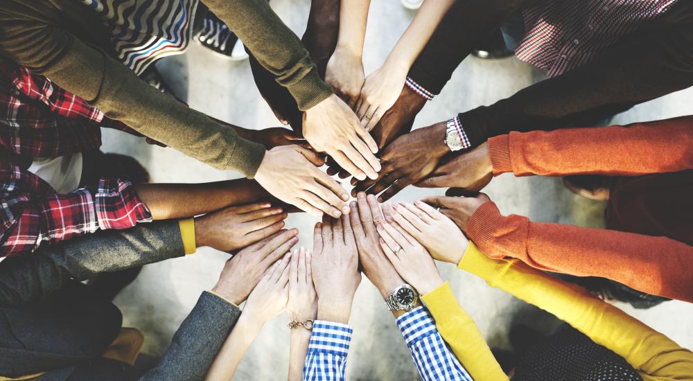 Many peoples' hands in the center of a circle.