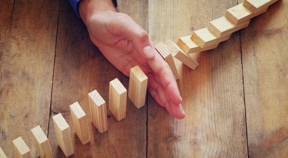 hand stopping row of dominos from falling