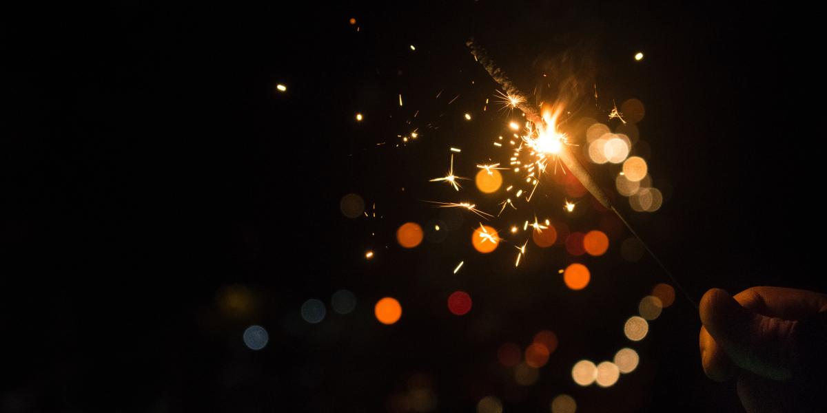 Hand holding a sparkler against a black background