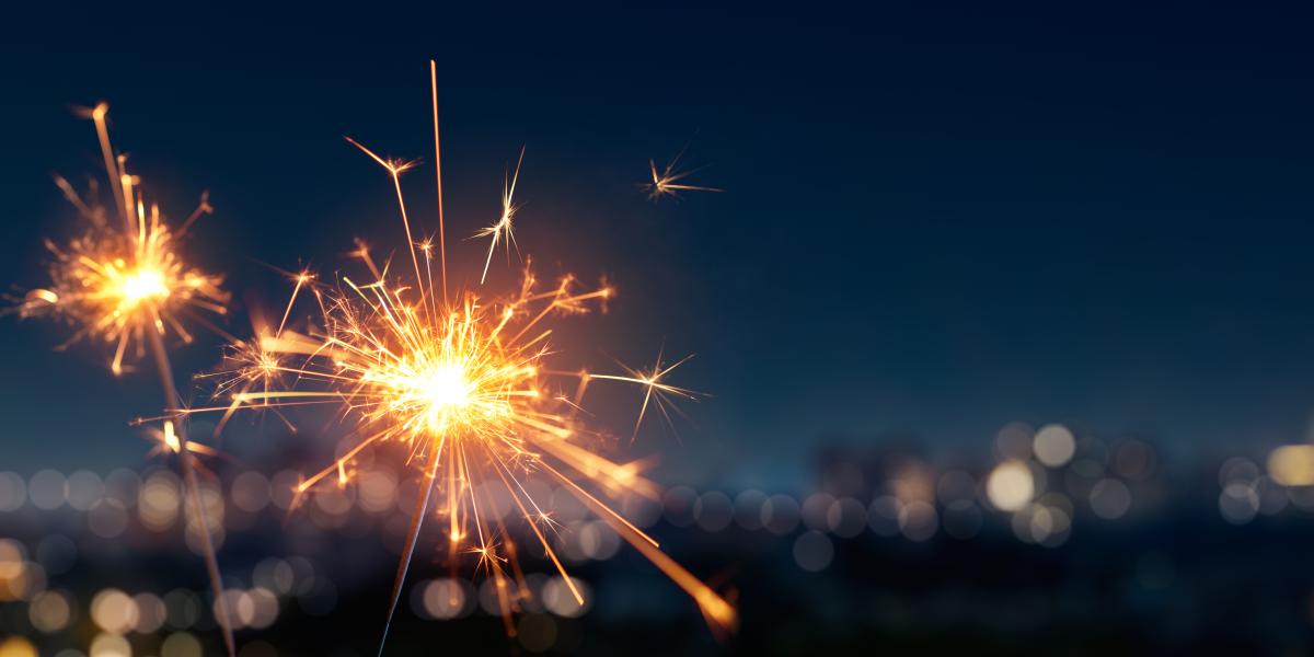 Two sparklers lit with a city skyline in the background