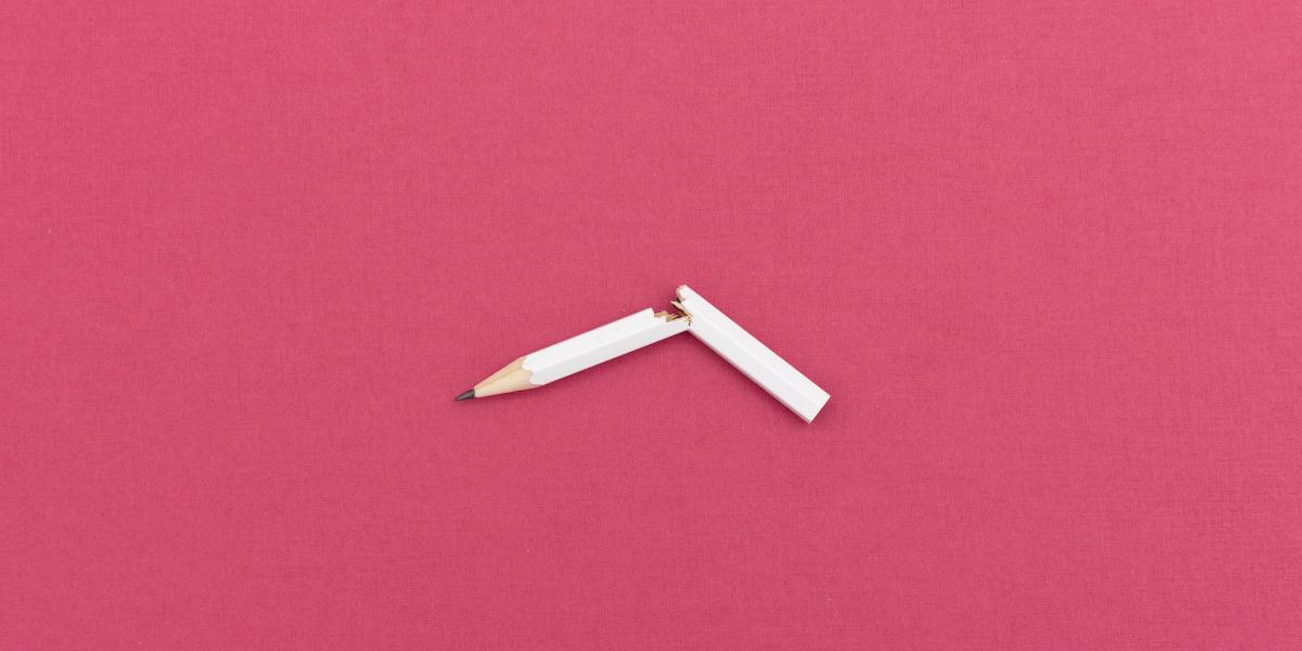 broken white pencil on pink background