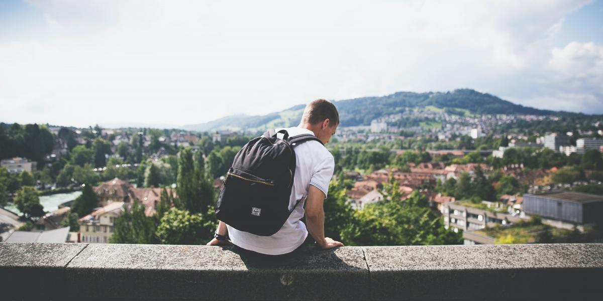 student sitting on a wall overlooking a city