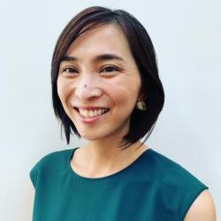 Woman with short black hair, wearing a green sleeveless top against a white background