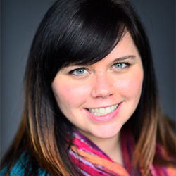 A woman with brown hair and a colorful scarf smiles at the camera