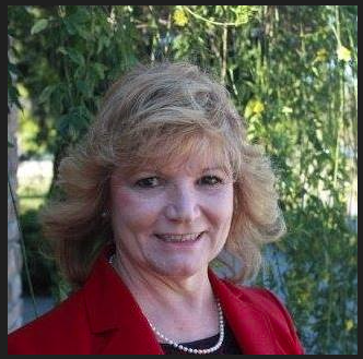 Mary-Ellen sit outside, wearing a red blazer 