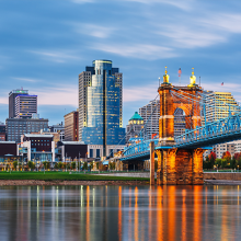 Cityscape of Cincinnat, OH with bridge and water in foreground