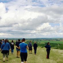 A group of students walks across a green hill.