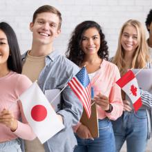 Five students standing in a line holding flags from different countries.