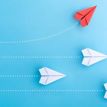 different colored paper planes on a blue background