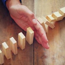 hand stopping row of dominos from falling