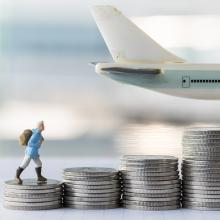 small figuring climbing piles of silver coins in front of toy plane